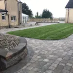 grass patch surrounded by paved concrete blocks